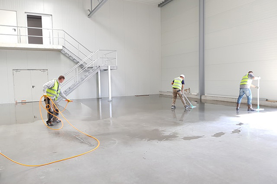 Workers cleaning warehouse floor