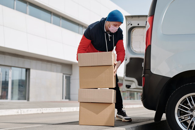 Man lifting boxes out of a van.